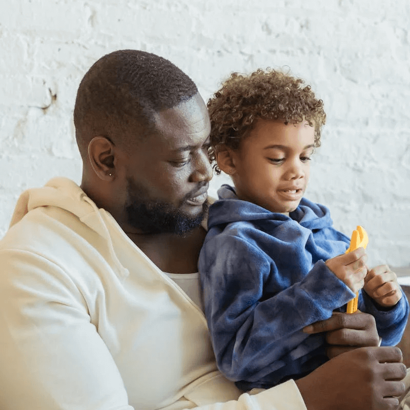 alt=’A man sitting with a child on his lap, both sharing a moment of joy and connection’, aria-hidden=’true’